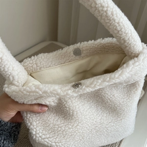 Detail of white faux fur tote bag showing interior lining and silver magnetic closure