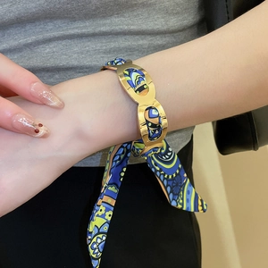 Close-up of a French vintage scarf-wrapped metal bangle with blue floral silk on wrist