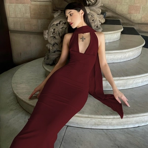 Détail de la robe longue en maille bordeaux à licou avec fente sur les marches en marbre