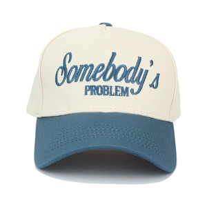 Detail of embroidered Somebody's PROBLEM text on off-white and blue trucker hat