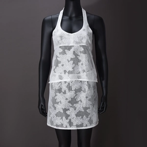 Close-up of white floral lace fabric and mesh texture on halter top and skirt set