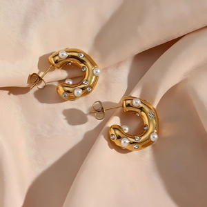 Detail of 18K gold-plated C-shaped hoop earrings featuring inset pearls and sparkling zircons