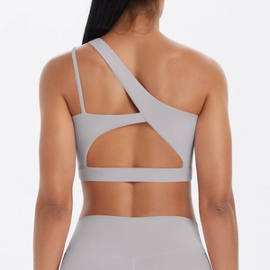 Detail of light grey sports bra featuring asymmetrical back cross straps and hollow design