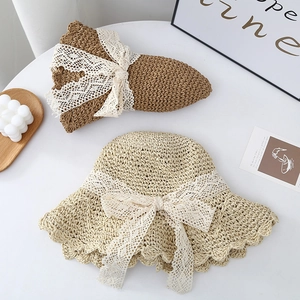 Detailed close-up of straw sun hats with white lace bow ties and woven textures