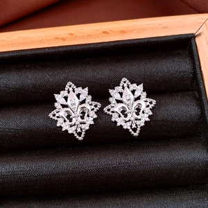 Macro shot of silver fleur-de-lis earrings with white cubic zirconia in a jewelry box