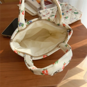 Close-up of quilted floral bag with zipper closure and cute bear pattern on wooden table