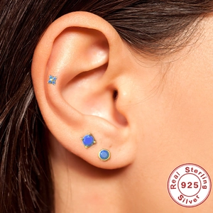Close-up of three blue gemstone S925 sterling silver stud earrings worn on a model ear