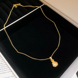 Macro detail of gold lucky bag pendant with zircon inlay on a black velvet jewelry box