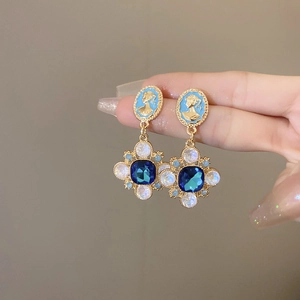Détail de boucles d'oreilles camée vintage avec cristal bleu et fleurs en opale