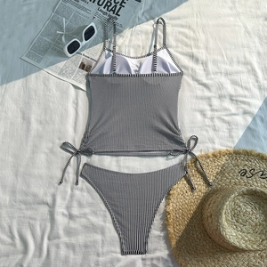 Flat lay of black and white striped bikini set with beach hat and stylish sunglasses