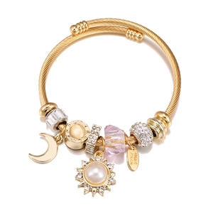 Detailed top view of gold beaded bracelet with moon, sun pearl, and pink crystal charms