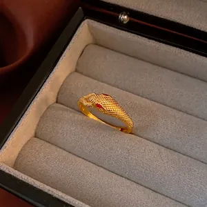 Vintage gold snake ring with red gem eyes and realistic scale texture in jewelry box