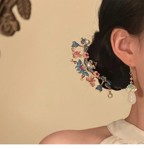 Gros plan sur l'épingle à cheveux papillon et boucles d'oreilles en émail et perles