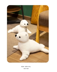 Détail de deux peluches de phoque blanc doux sur un parquet dans un décor chaleureux