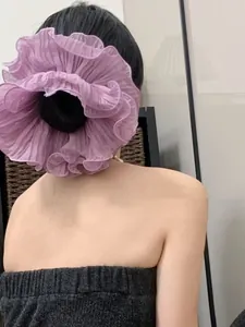 Detailed view of an oversized purple pleated chiffon scrunchie on a model back hair