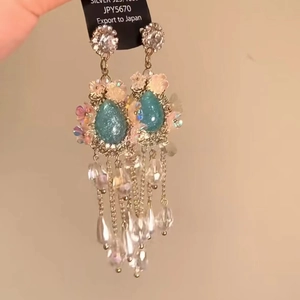 Detail view of silver flower earrings with blue teardrop pendant and hanging bead chains