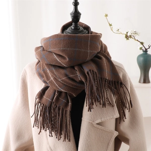 Close-up of brown plaid scarf with tassels made of warm soft cashmere-like fabric