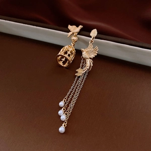 Detailed view of asymmetric birdcage and phoenix earrings with pearl tassels in gold