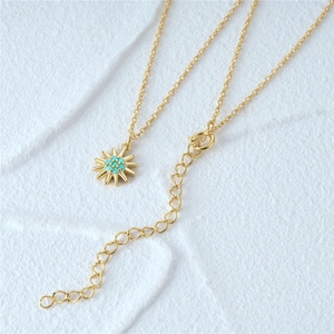 Macro shot of 925 silver sunburst pendant with turquoise inlay and gold link chain
