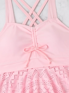 Detailed view of pink swim top featuring criss-cross straps and delicate lace hem detail