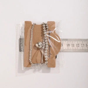 Silver bead bracelet with heart pendant measured on ruler showing 18cm length