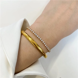 Close-up of a stackable 18K gold plated bangle and a sparkling diamond tennis bracelet