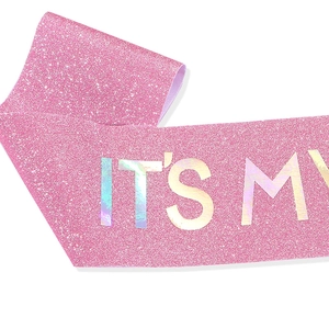 Detail of pink glitter sash with holographic It's My Birthday lettering for parties