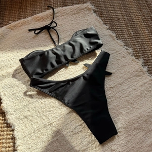 Close-up of black bandeau bikini set with starfish embroidery on natural straw mat