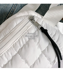 Detail of white quilted nylon bag featuring smooth silver zipper and nylon strap