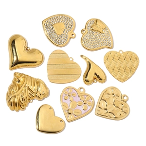 Assortimento di ciondoli a cuore dorati con strass e dettagli floreali su sfondo bianco