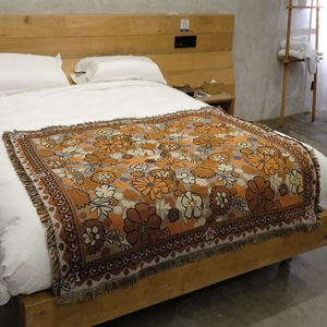 Close-up of vintage floral woven blanket featuring orange daisies and fringe detail