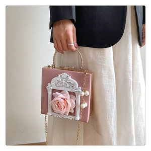 Detail of pink baroque handbag with 3D rose relief, golden handle and pearl charm accessory