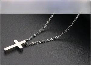 Detailed view of a polished silver cross pendant with a fine cable link chain necklace