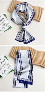 Detail of navy blue and white silk scarf with geometric chain pattern on a tray