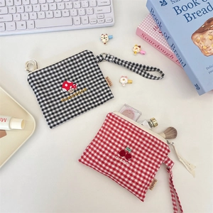 Close-up of checkered canvas pouches with mushroom and cherry embroidery for storage