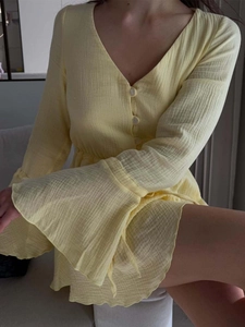 Detail of yellow V-neck mini dress with flared sleeves and button-down front in textured cotton