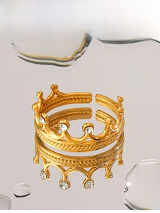 Détail d'une bague couronne dorée avec cristaux et anneau tressé sur surface réfléchissante