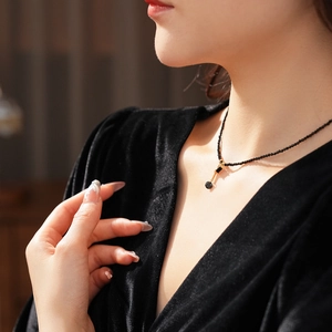 Detail of elegant black beaded necklace with golden musical note pendant on female model
