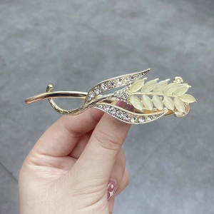 Detail of golden wheat-shaped hair clip with shimmering rhinestones and opal stones
