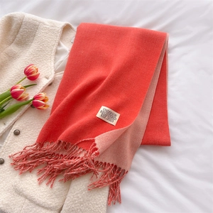 Detailed shot of double-sided cashmere-style scarf in coral and pink with tassel fringe
