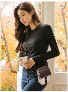 Close-up of stylish two-tone mini crossbody bag in dark brown and white with metal buckle
