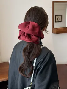 Detailed view of an oversized burgundy satin scrunchie with elegant fabric texture