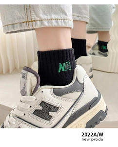 Close-up of black cotton socks with green NA embroidery and classic leather sneakers