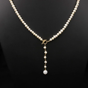 Elegant natural pearl long necklace with golden OT clasp on a black velvet mannequin bust