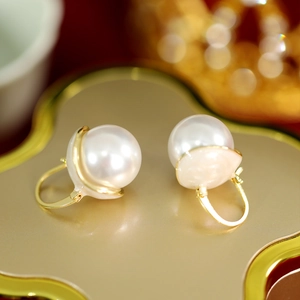 Macro shot of elegant round white pearl earrings with gold U-shaped metal clasps