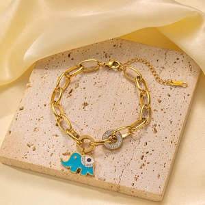 Detalle de pulsera dorada de eslabones con amuleto de elefante y ojo turco en seda