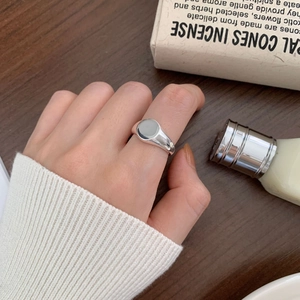 Macro shot of minimalist silver signet ring showing polished oval surface on finger