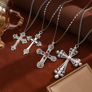 Detailed shot of four silver cross necklaces with crystals and pearls on velvet