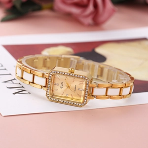 Detail of square gold watch with white ceramic bracelet and rhinestone bezel decoration