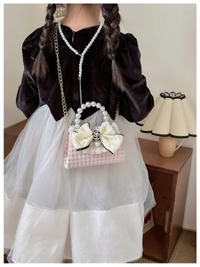 Detail of pink houndstooth girl bag with pearl handle and camellia bow accessory